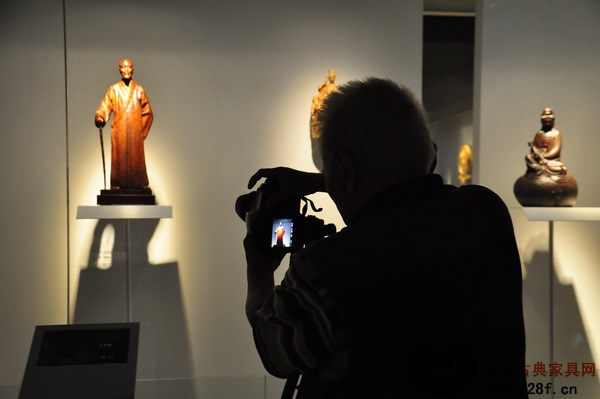 精致的木雕作品吸引了一位老者拍照留念 精致的木雕作品吸引了一位老者拍照留念