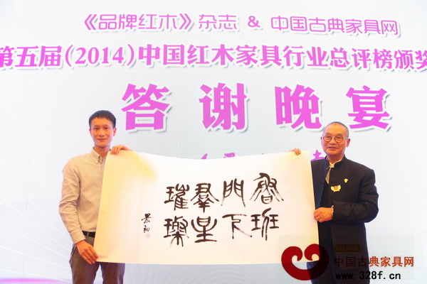 胡景初老師（右）的墨寶“魯班門下群星璀璨”被中山市區(qū)氏臻品總經(jīng)理區(qū)錦澤（左）拍得 