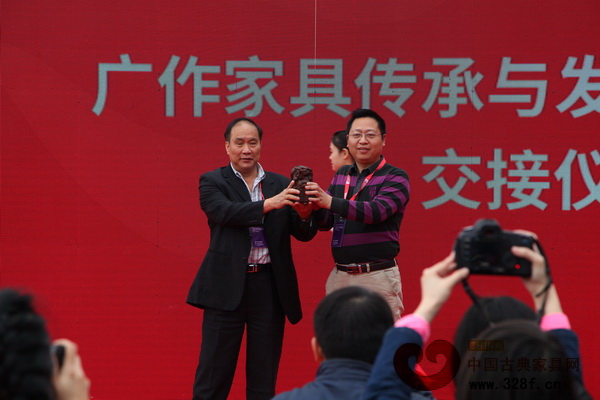 廣作家具傳承與發(fā)展聯(lián)合會交接儀式同期舉行，新會區(qū)古典家具商會會長袁秋耘（右）從中山市紅木家具行業(yè)協(xié)會會長蕭照興手中接過聯(lián)合會輪值主席玉璽 