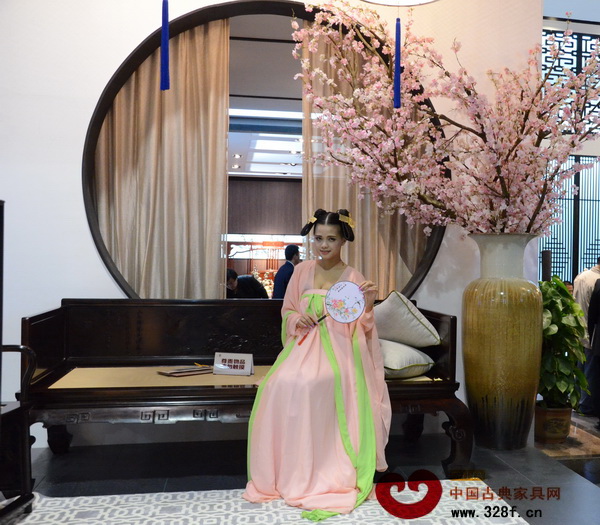 東莞名家具展的明堂紅木的展廳外，一位身穿漢服的古典美人笑意盈盈，相得益彰