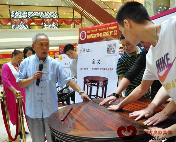 王秀林請消費(fèi)者觸摸“大紅酸枝·明式枕環(huán)月牙桌”平滑的桌面 