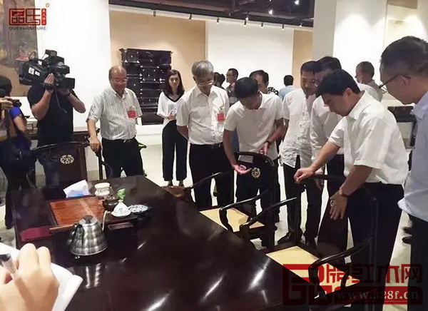 區(qū)氏臻品總經(jīng)理區(qū)錦澤（右五）為調(diào)研團介紹其紅木家具的工藝特色 