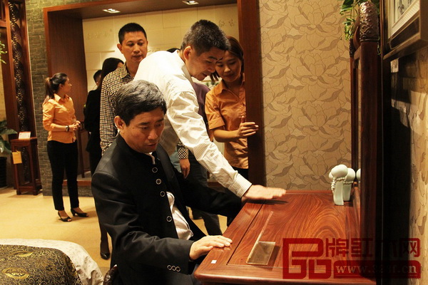 中國(guó)家具協(xié)會(huì)理事長(zhǎng)朱長(zhǎng)嶺仔細(xì)地體驗(yàn)和欣賞紅古軒的紅木家具