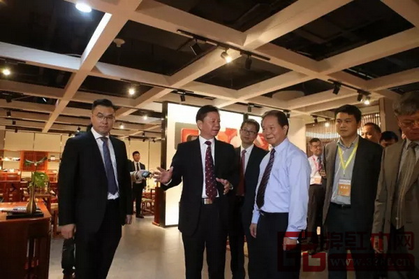 國壽紅木董事長陳國壽（左二）為原廣東省常務(wù)副省長湯炳權(quán)（右三）介紹現(xiàn)場展品