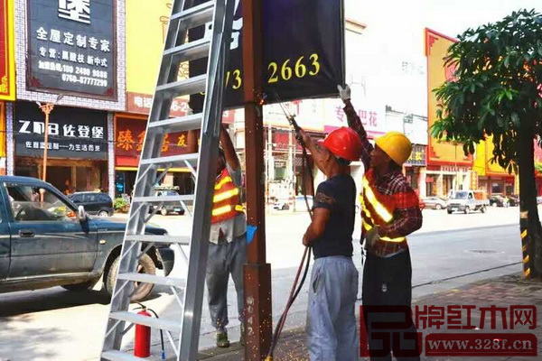 城管執(zhí)法人員在中山市大涌鎮(zhèn)紅木企業(yè)集聚路段拆除違規(guī)燈旗廣告