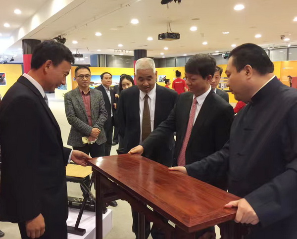 太和木作創(chuàng)始人關(guān)毅（右一）在展覽會(huì)現(xiàn)場(chǎng)為中宣部對(duì)外推廣局張雁彬局長(zhǎng)（右二）及北京市外宣辦等領(lǐng)導(dǎo)介紹京作硬木家具制作技藝