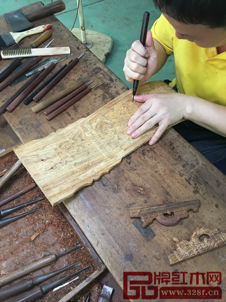 區(qū)氏臻品的雕花師傅正在交椅的獨板靠背上雕刻螭龍捧壽紋