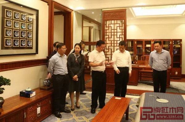 中國傳統(tǒng)工藝大師、國壽紅木董事長陳國壽（左三）為考察團一行人介紹國壽紅木樣板房設計理念