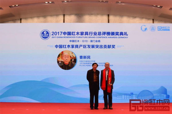 全國(guó)工商聯(lián)第十一屆執(zhí)委、全聯(lián)民間文物藝術(shù)品商會(huì)特邀會(huì)長(zhǎng)、全聯(lián)民間文物藝術(shù)品商會(huì)藝術(shù)紅木家具專業(yè)委員會(huì)會(huì)長(zhǎng)宋建文（左）為“中國(guó)紅木家具產(chǎn)區(qū)發(fā)展突出貢獻(xiàn)獎(jiǎng)”獲獎(jiǎng)?wù)摺都t木家具通用技術(shù)條件》國(guó)家標(biāo)準(zhǔn)主要起草人曹新民頒發(fā)獎(jiǎng)杯