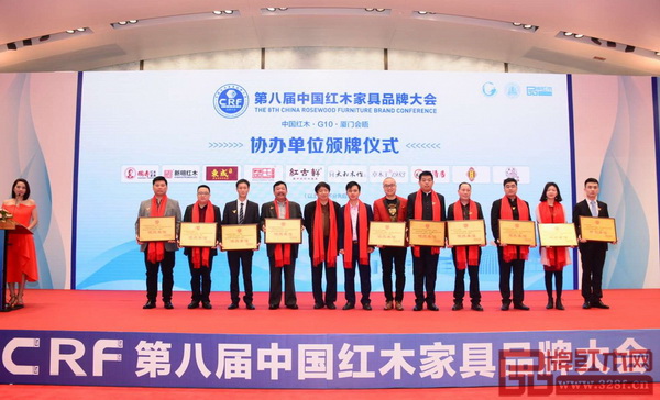 國壽紅木副總經(jīng)理王耀佳（左一）上臺接受第八屆中國紅木家具品牌大會協(xié)辦單位頒牌
