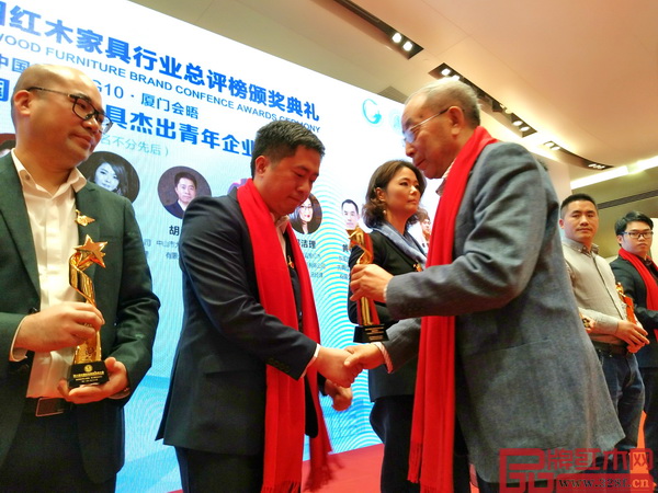 中國紅木家具技術專家曹新民為大匯堂董事長胡春龍頒發(fā)杰出青年企業(yè)家獎杯
