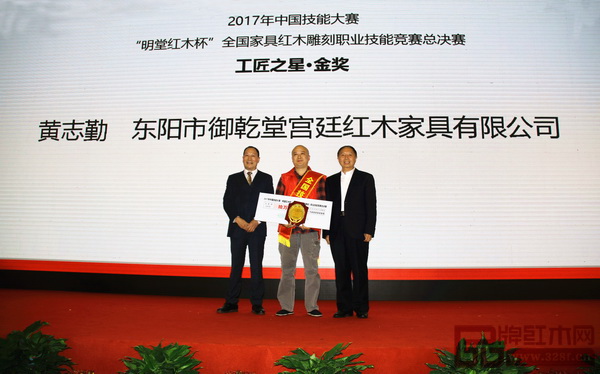 第十一屆全國(guó)政協(xié)提案委員會(huì)副主任、原勞動(dòng)和社會(huì)保障部副部長(zhǎng)、中國(guó)輕工業(yè)聯(lián)合會(huì)原會(huì)長(zhǎng)步正發(fā)（右一）為御乾堂選手黃志勤頒發(fā)“工匠之星·金獎(jiǎng)”牌匾，御乾堂紅木董事長(zhǎng)馬海軍上臺(tái)見證