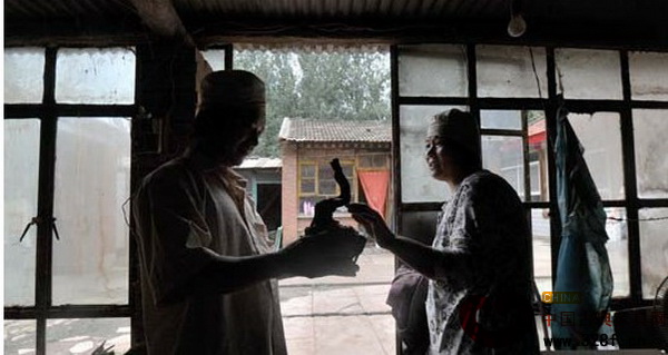 丁廣軍和妻子商量把一塊木料雕刻成什么造型