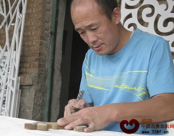 劉迎生正在專注地雕刻作品