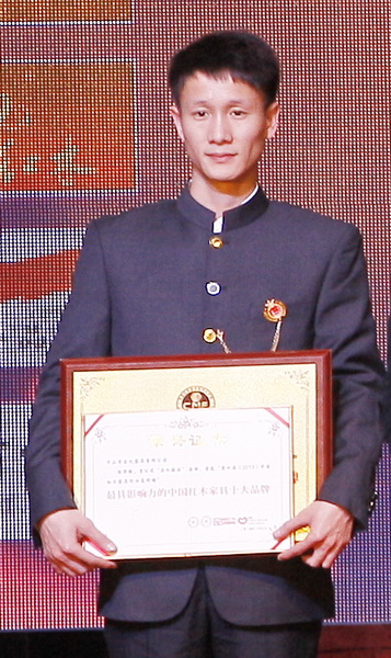 區(qū)氏臻品總經(jīng)理區(qū)錦澤上臺接受“2013年最具影響力的中國紅木家具十大品牌”獎牌與證書的授予