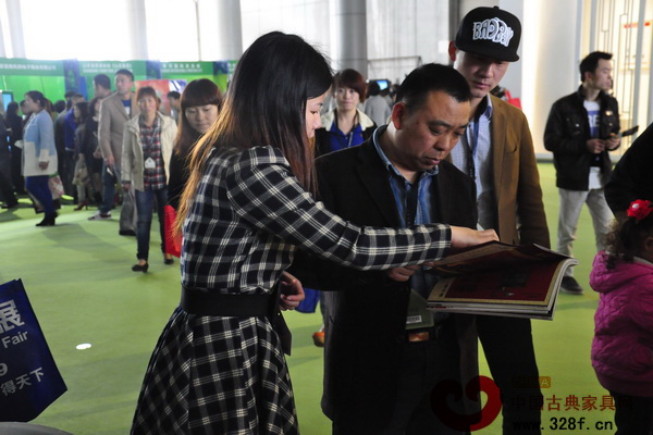 中國(guó)古典家具網(wǎng)、《品牌紅木》工作人員向參展者介紹雜志
