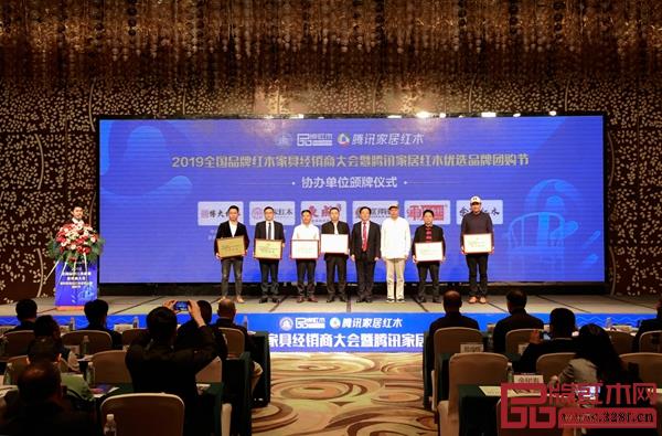 2019全國(guó)品牌紅木家具經(jīng)銷商大會(huì)暨騰訊家居紅木優(yōu)選品牌團(tuán)購(gòu)節(jié)協(xié)辦單位頒牌，水雨軒董事長(zhǎng)廖升中（左三）上臺(tái)領(lǐng)牌