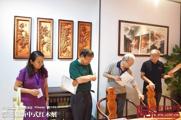 全國工商聯(lián)第十一屆執(zhí)委、全聯(lián)民間文物藝術(shù)品商會創(chuàng)會會長宋建文（左二）、全聯(lián)民間文物藝術(shù)品商會藝術(shù)紅木家具專業(yè)委員會專家顧問蘇垣（右二）、全聯(lián)民間文物藝術(shù)品商會藝術(shù)紅木家具專業(yè)委員會專家顧問曹新民（右一）等專家評委來到良辰軒紅木展區(qū)對《東方·山水》茶臺進(jìn)行品鑒、評分