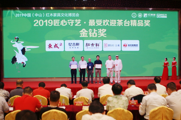 東成·文宋《和風茶臺》榮獲“2019匠心守藝·最受歡迎茶臺精品獎·金鉆獎”,東成紅木市場總監(jiān)阮家鵬(左一)代表上臺領(lǐng)獎 東成·文宋《和風茶臺》榮獲“2019匠心守藝·最受歡迎茶臺精品獎·金鉆獎”,東成紅木市場總監(jiān)阮家鵬(左一)代表上臺領(lǐng)獎