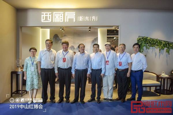 中國(guó)林業(yè)產(chǎn)業(yè)聯(lián)合會(huì)副會(huì)長(zhǎng)宋維明（左三），國(guó)家林業(yè)和草原局森林資源管理司原副司長(zhǎng)張松丹（左二），中山市大涌鎮(zhèn)鎮(zhèn)長(zhǎng)賀修虎（右四），全聯(lián)藝術(shù)紅木家具專業(yè)委員會(huì)專家顧問(wèn)華南農(nóng)業(yè)大學(xué)博士生導(dǎo)師李凱夫（右二）、教育部教學(xué)改革示范專業(yè)“家具設(shè)計(jì)與制造”專業(yè)帶頭人彭亮（右三）、華南農(nóng)業(yè)大學(xué)研究生導(dǎo)師郭瓊（左一）、全聯(lián)藝術(shù)紅木家具專業(yè)委員會(huì)執(zhí)行會(huì)長(zhǎng)林偉華（右一）參觀憶古軒并與董事長(zhǎng)劉定杰（左四）合影