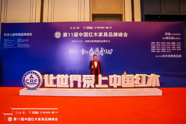 大匯堂董事長(zhǎng)胡春龍?jiān)诒緦眉t木品牌峰會(huì)主題展板前留影