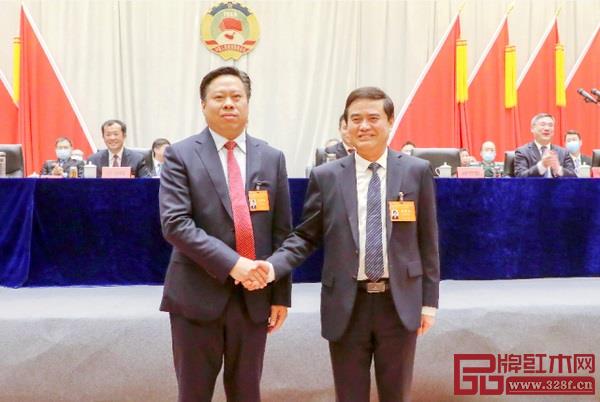 監(jiān)利市政協(xié)上屆主席湯吉銀（右）和新當(dāng)選的市政協(xié)主席廖和平（左）在主席臺前握手交接