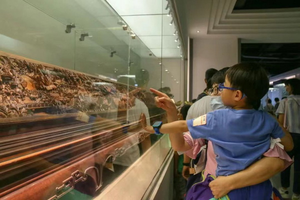    一對(duì)母子正在觀賞黃花梨清明上河圖木雕作品